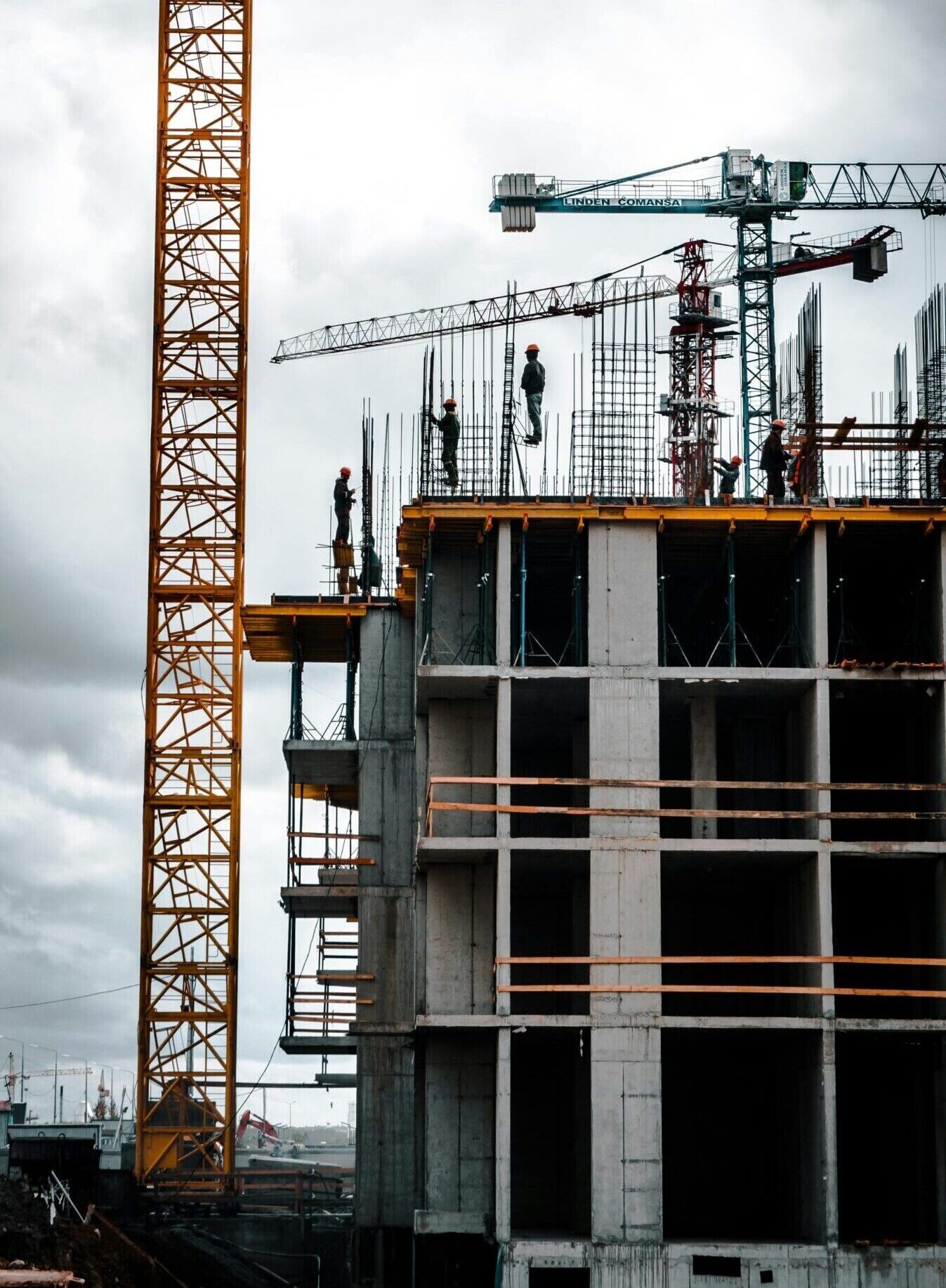 Vertical view of a construction site with cranes and workers building a skyscraper.